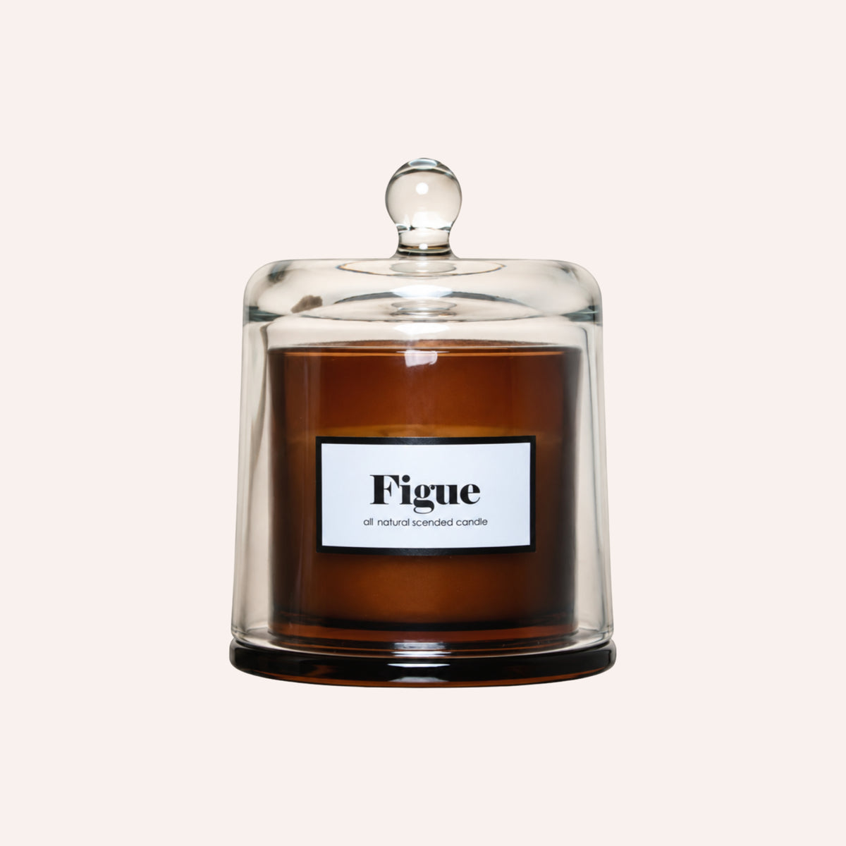 A Figue scented wax candle in an amber glass jar with a clear glass dome lid, shown against a solid off-white background.